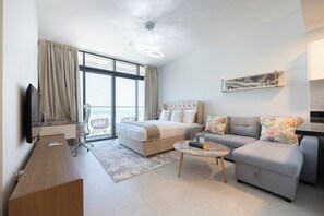 A modern hotel room with a bed, sofa, and a small coffee table.