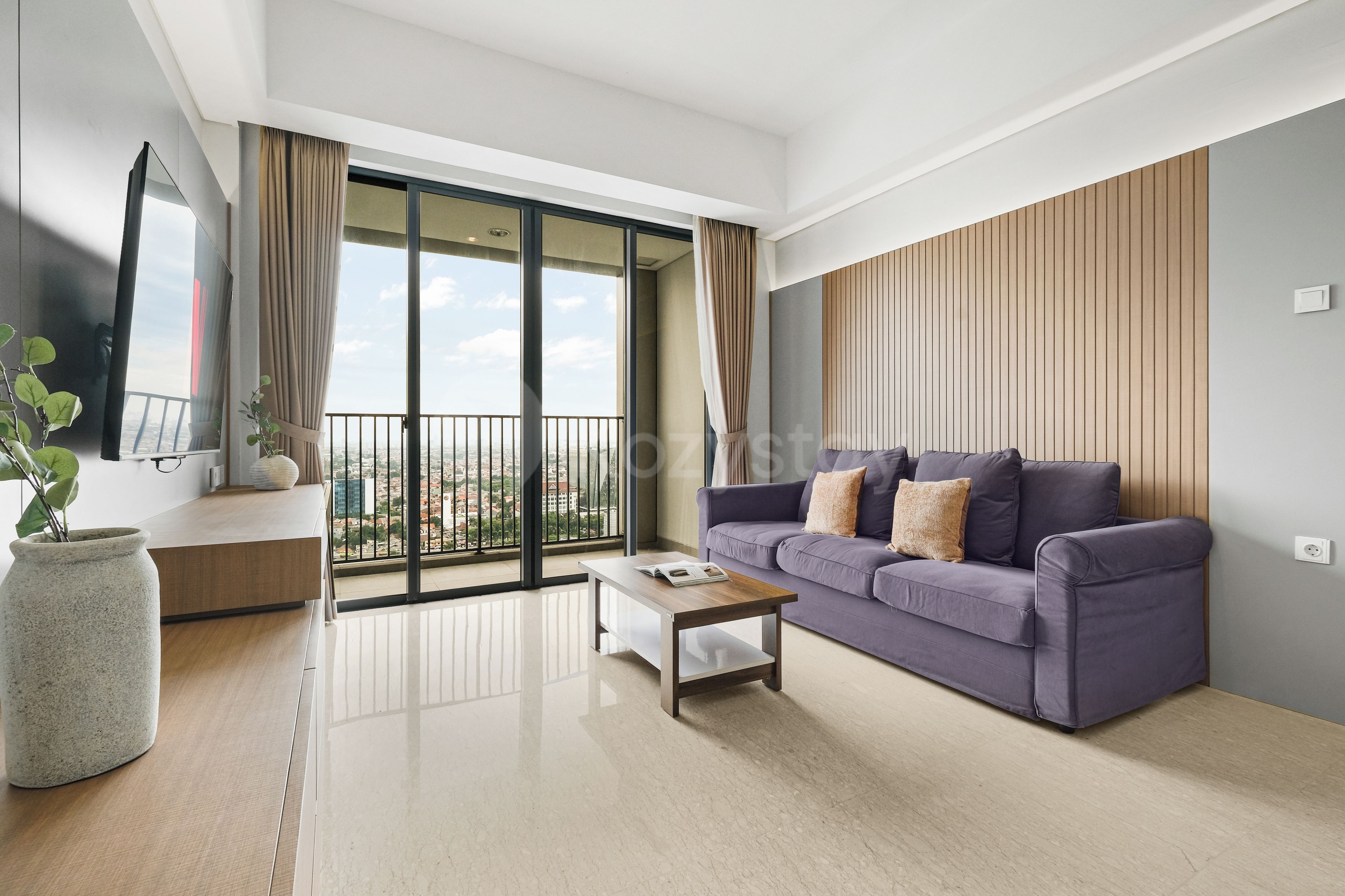 A modern living room with a sofa, coffee table, and a large window with a city view.