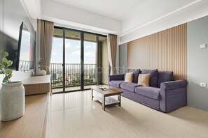 A modern living room with a sofa, coffee table, and a large window with a city view. - Chiro by Kozystay - Tanjung Barat (Jakarta)