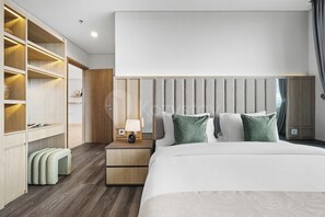 A modern hotel room with a large bed, a bedside table with a lamp, a wardrobe with shelves, and a view of the city. - Chiro by Kozystay - Tanjung Barat (Jakarta)