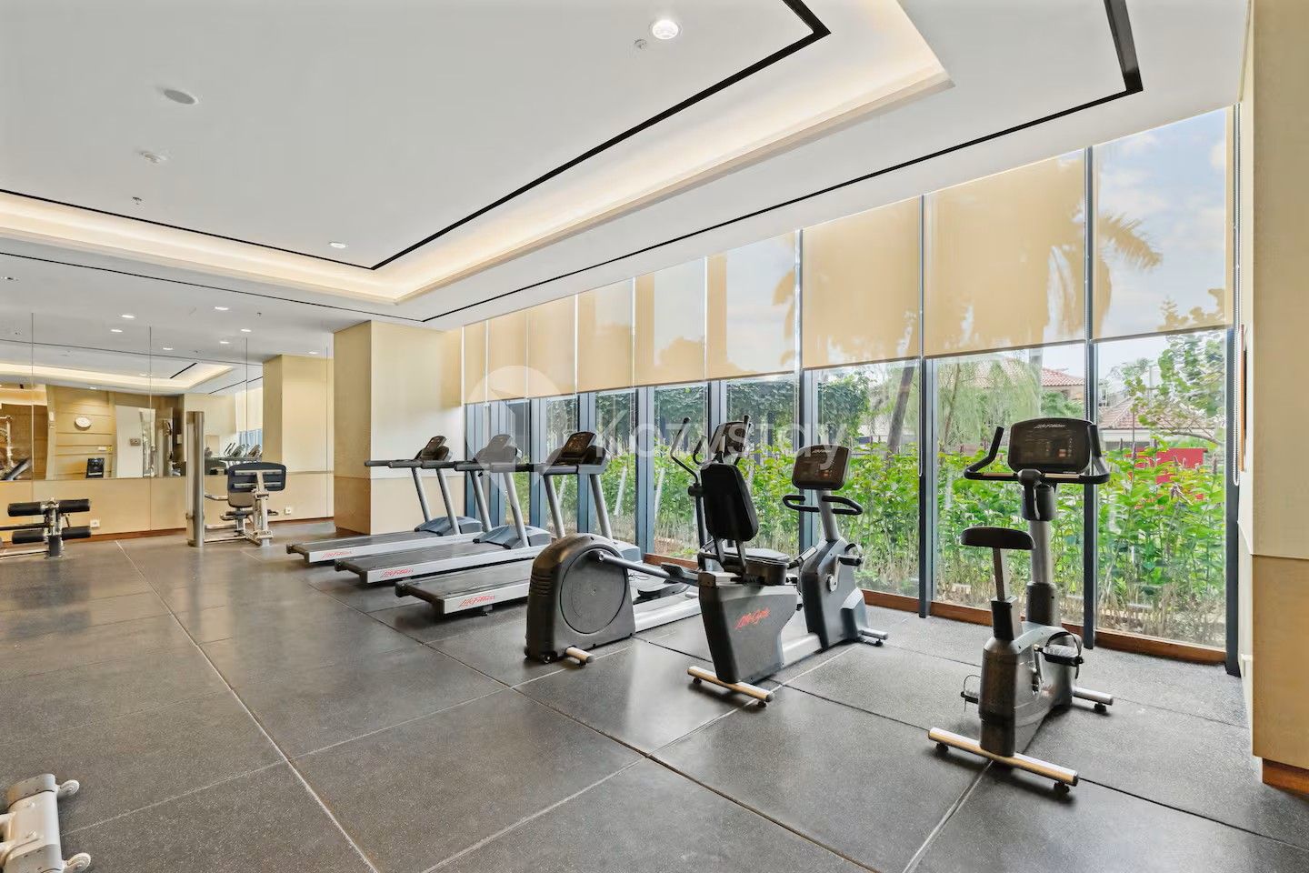 Un gimnasio moderno con cintas de correr, elípticas y equipo de pesas.