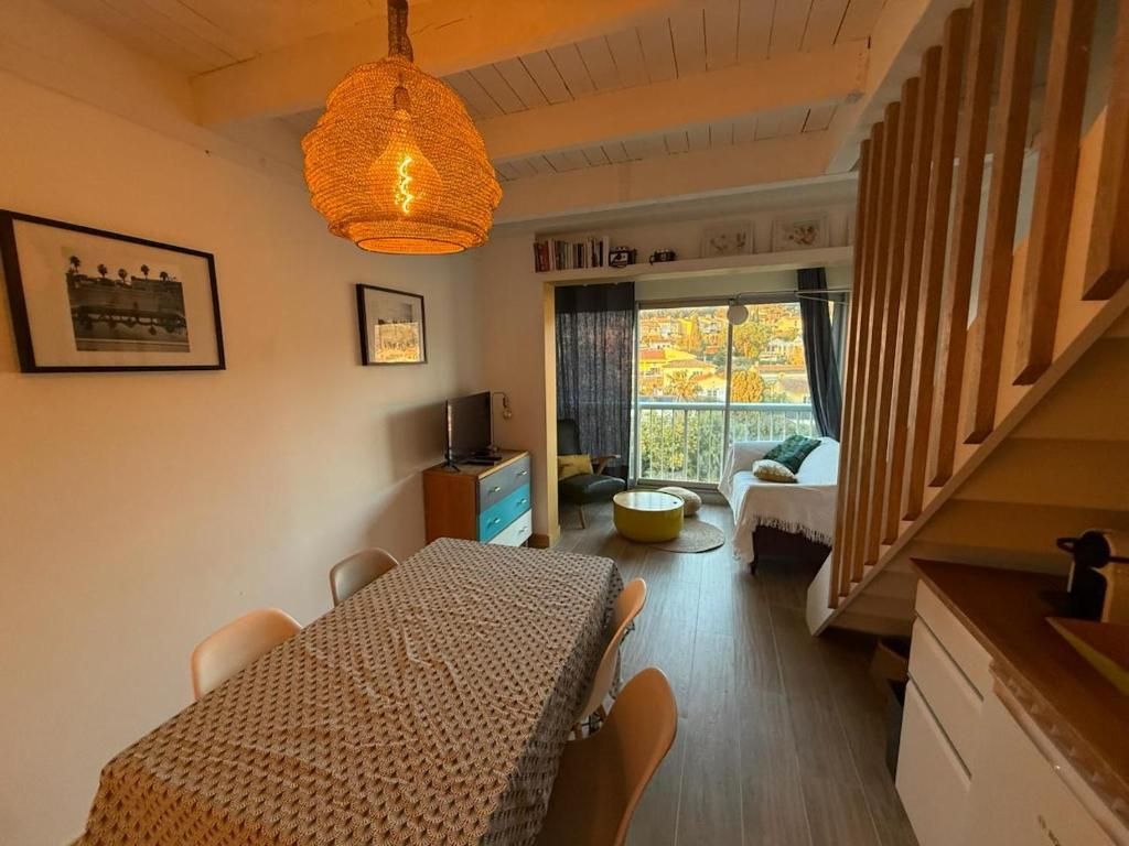 Une pièce comprenant une table à manger, des chaises, un luminaire suspendu, un lit avec vue et un escalier.