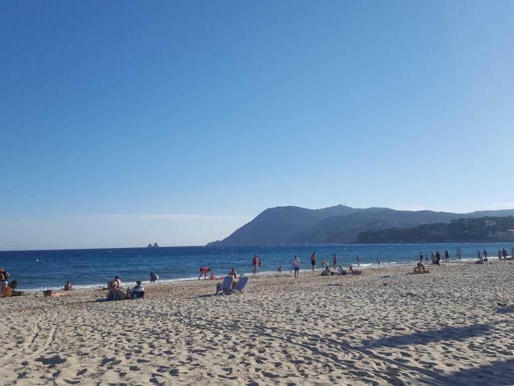 A beach with people, a clear sky, and distant hills.