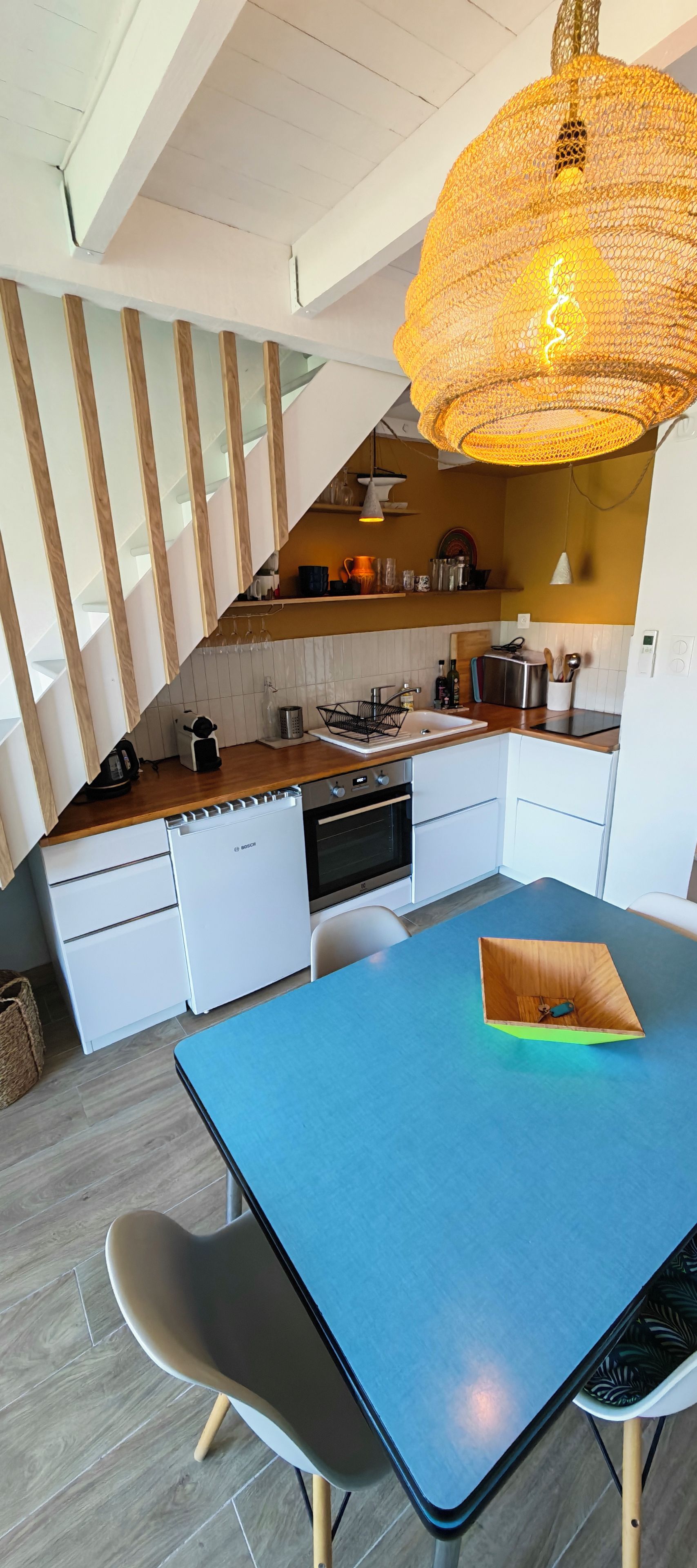 Eine moderne Küche mit weißen Schränken, einem Backofen von Bosch und einem blauen Esstisch.