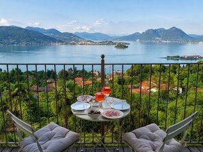 A balcony with a table set for two, overlooking a lake and mountains. - Villa Anna Isole Borromee No. 11 (Stresa)