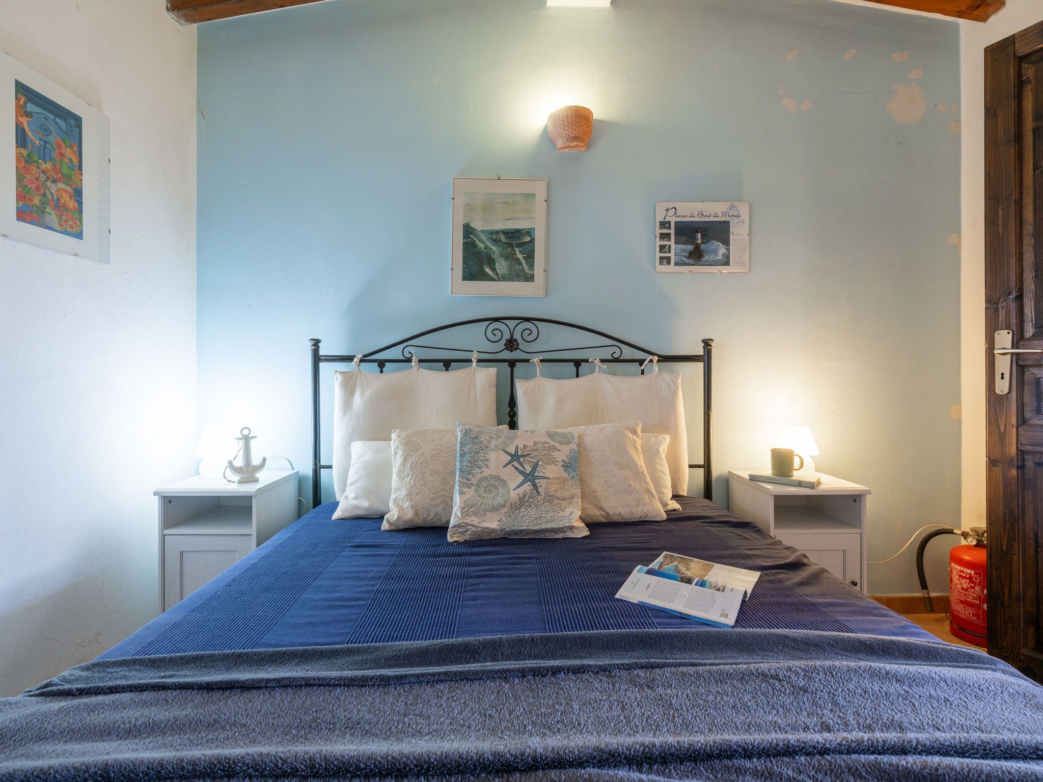 Una camera da letto con un letto, comodini, una lampada a parete e un estintore.