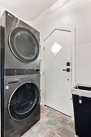 A laundry room with a double-door washing machine and a trash bin. - Historic Bruce Goff Home with Pool, Hot tub & Sauna near Utica Square (Tulsa)