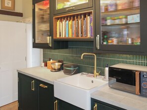 A kitchen with a white sink, a microwave, and a cabinet with a glass door containing books and kitchen items. - 4 bedroom accommodation in Montrose (Montrose)