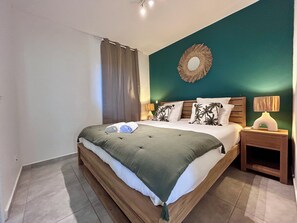 Ein Schlafzimmer mit einem Bett, zwei Nachttischen, einem Wandspiegel und einem Vorhang.