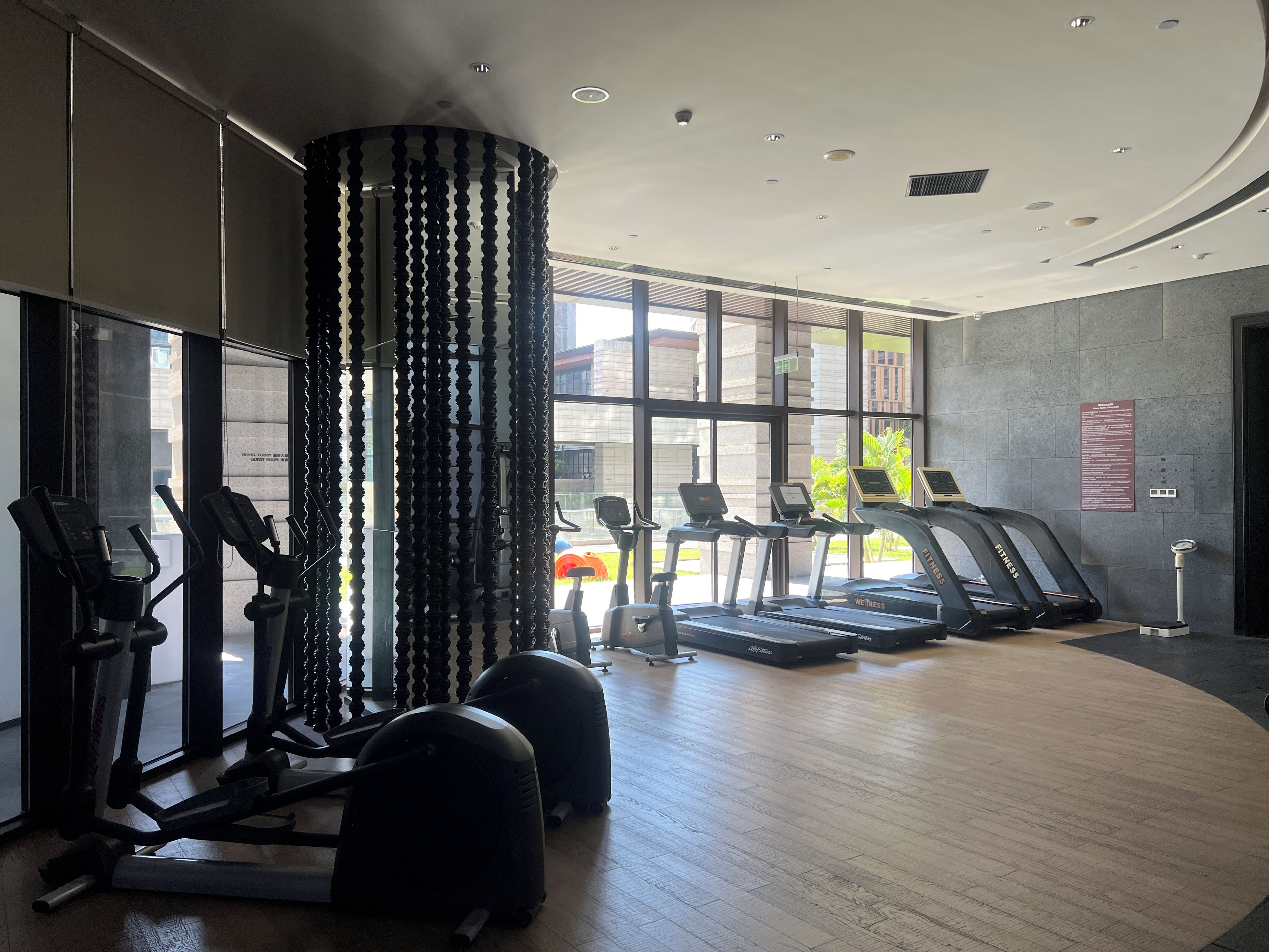 Un gimnasio con equipamiento de ejercicio, amplias ventanas y un diseño interior moderno.