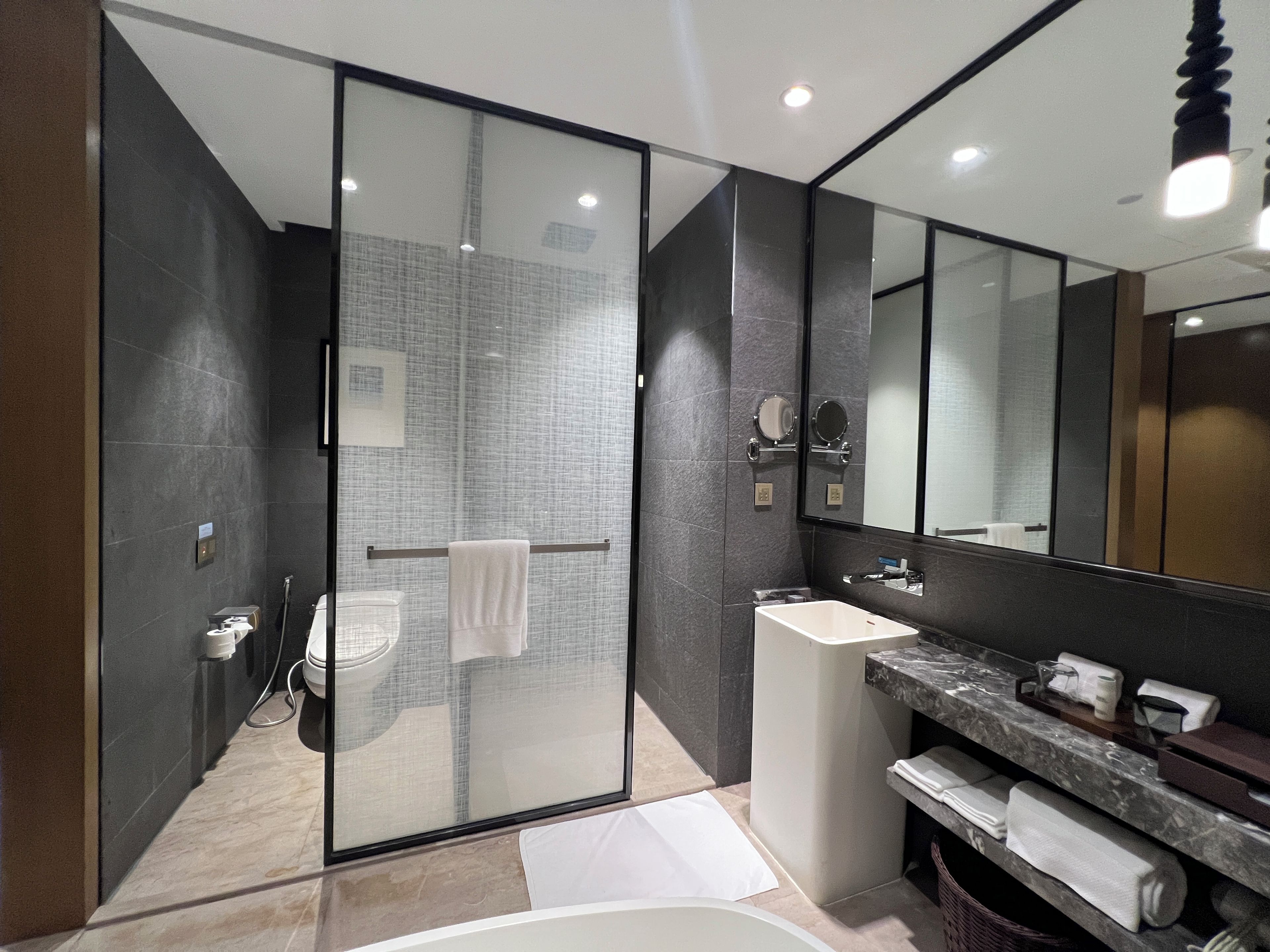 A modern bathroom with a glass shower enclosure, a vanity with a marble countertop, and a large mirror.