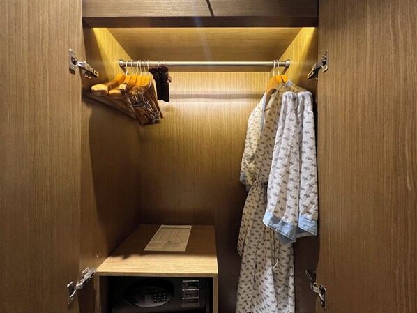 A walk-in closet with wooden doors, a metal rod for hanging clothes, and a small shelf with a paper.