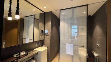 A modern bathroom with a glass partition, a sink, a mirror, and a toilet.