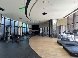 A gym with cardio equipment, weight machines, and a curved wooden floor.