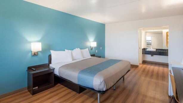 Una habitación de hotel con cama, mesitas de noche, escritorio y espejo.