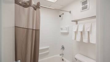 Ein Badezimmer mit Duschvorhang, Badewanne, Toilette und Handtuchhalter.