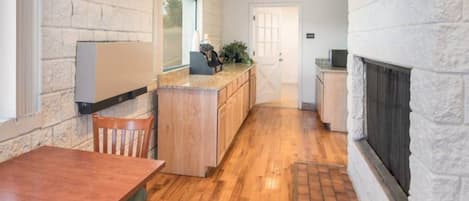 A kitchen with a wooden table, a counter, and a fireplace.