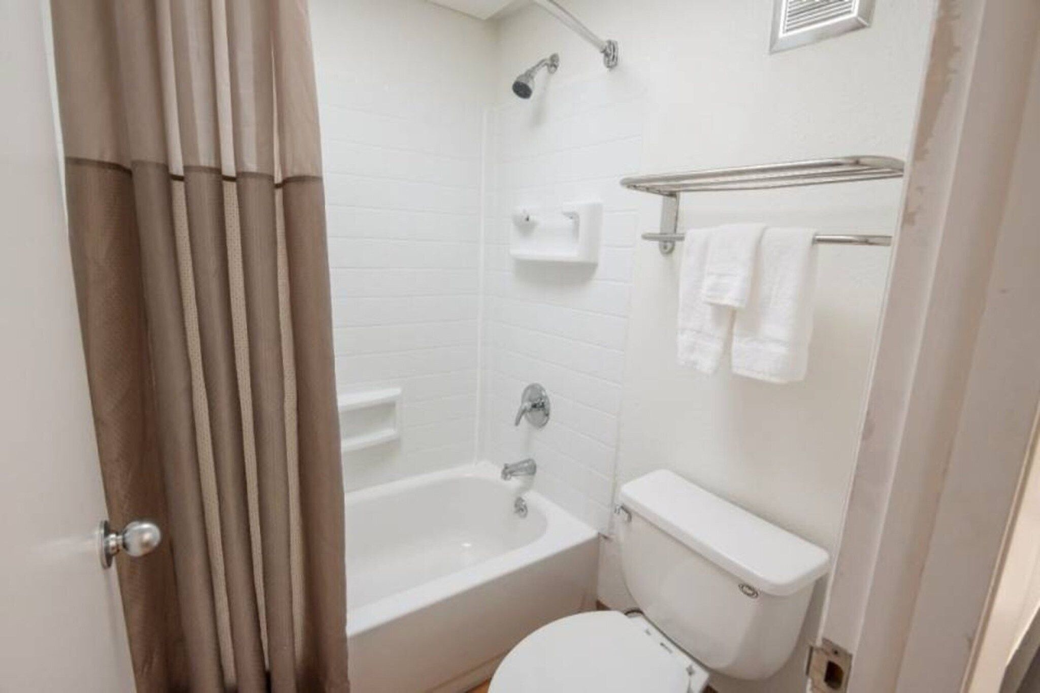 A small bathroom with a bathtub, toilet, and a showerhead.