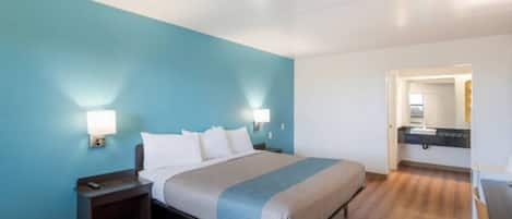 Une chambre d’hôtel comprenant un lit, des tables de chevet, une commode, un bureau et un miroir.