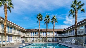Ein Hotel mit Schwimmbad, Palmen und blauem Himmel.