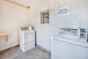 A laundry room with a washing machine, dryer, and a sign stating 'Motel 6 is not responsible for items left unattended.'