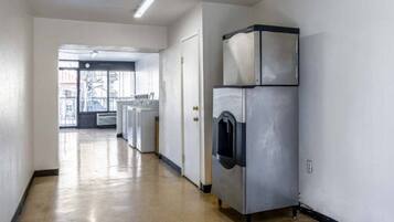 A laundry room with a large industrial washer and dryer, a door leading to another room, and a view of the outside through a window.