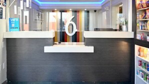 Una mesa de recepción con un gran número 6 encima, diseño moderno con acabado en madera oscura y un piso a rayas coloridas.