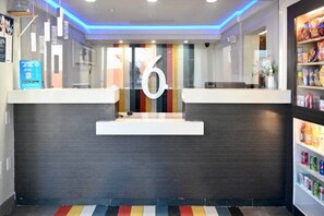 A reception desk with a large number '6' above it, a modern design with a dark wood finish, and a colorful striped floor. - 1 Queen Bed | Non-Smoking, Micfridge (Little Rock AR)