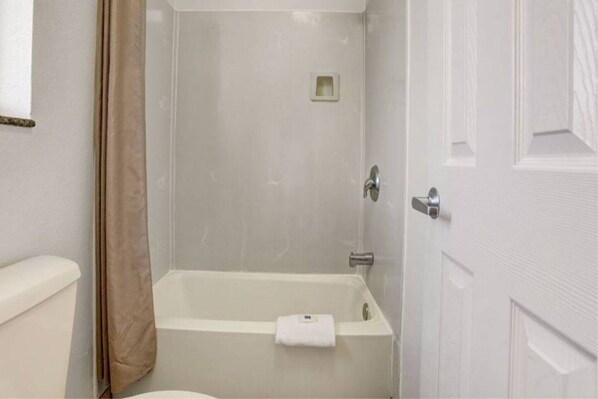 A bathroom with a bathtub, toilet, and a shower curtain.