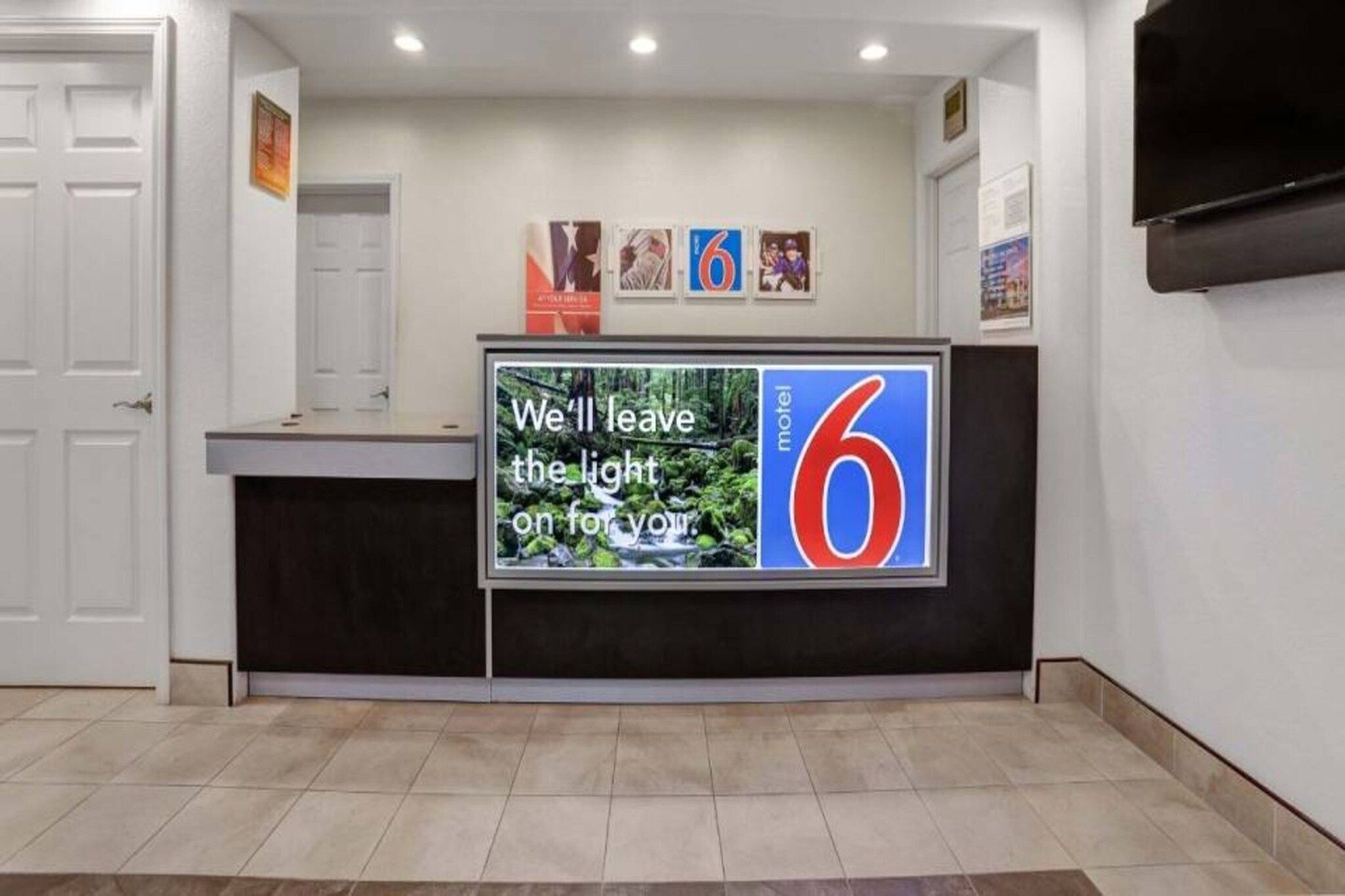 A reception desk with a digital display and a sign for a motel.