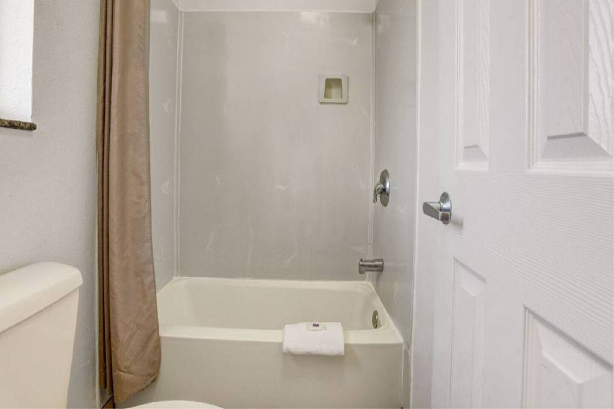 A bathroom with a bathtub, toilet, and a shower curtain.