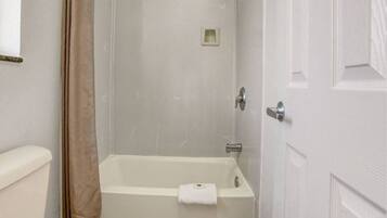 A bathroom with a bathtub, toilet, and a shower curtain.