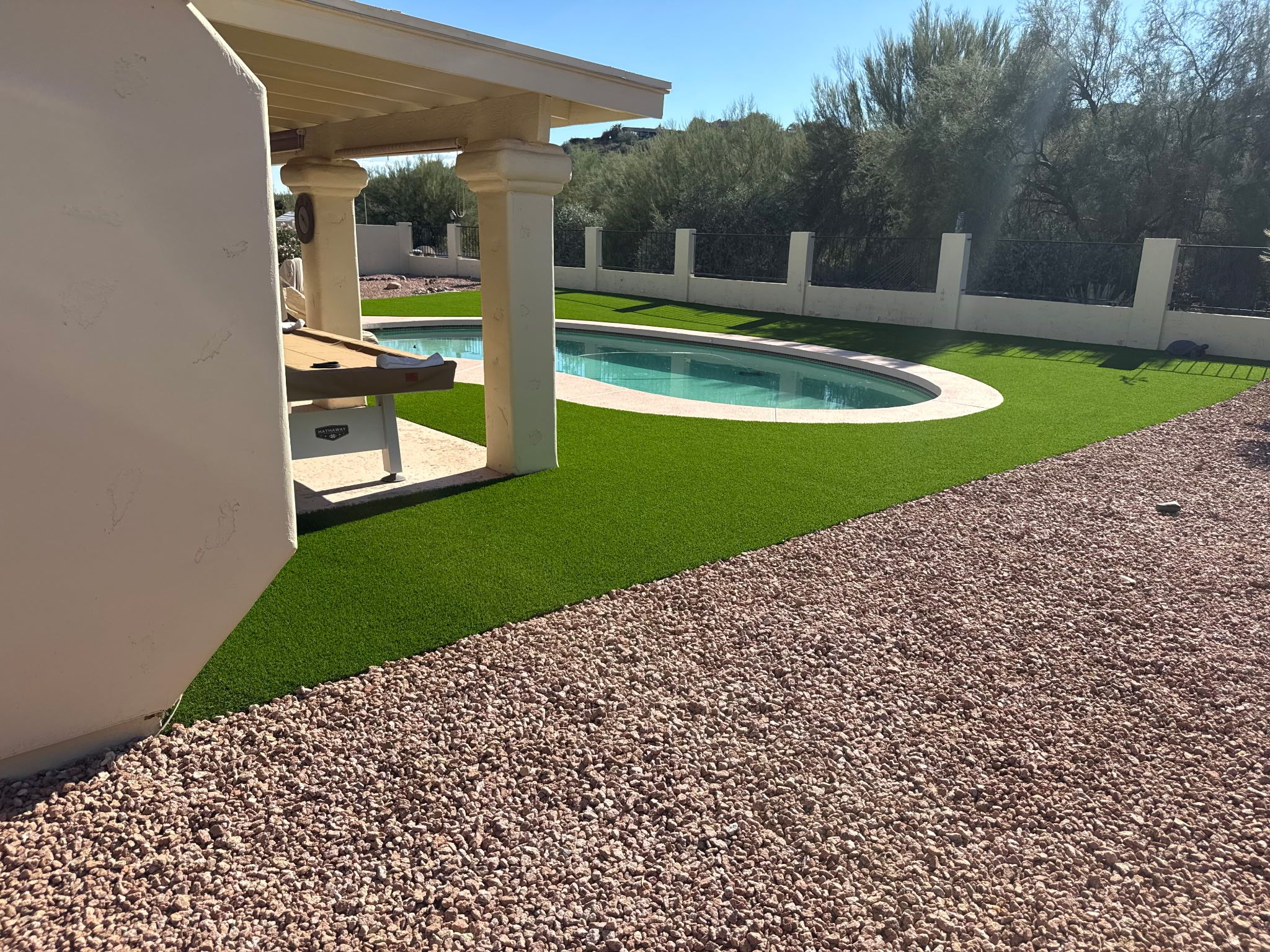 A swimming pool with artificial grass and a pergola.