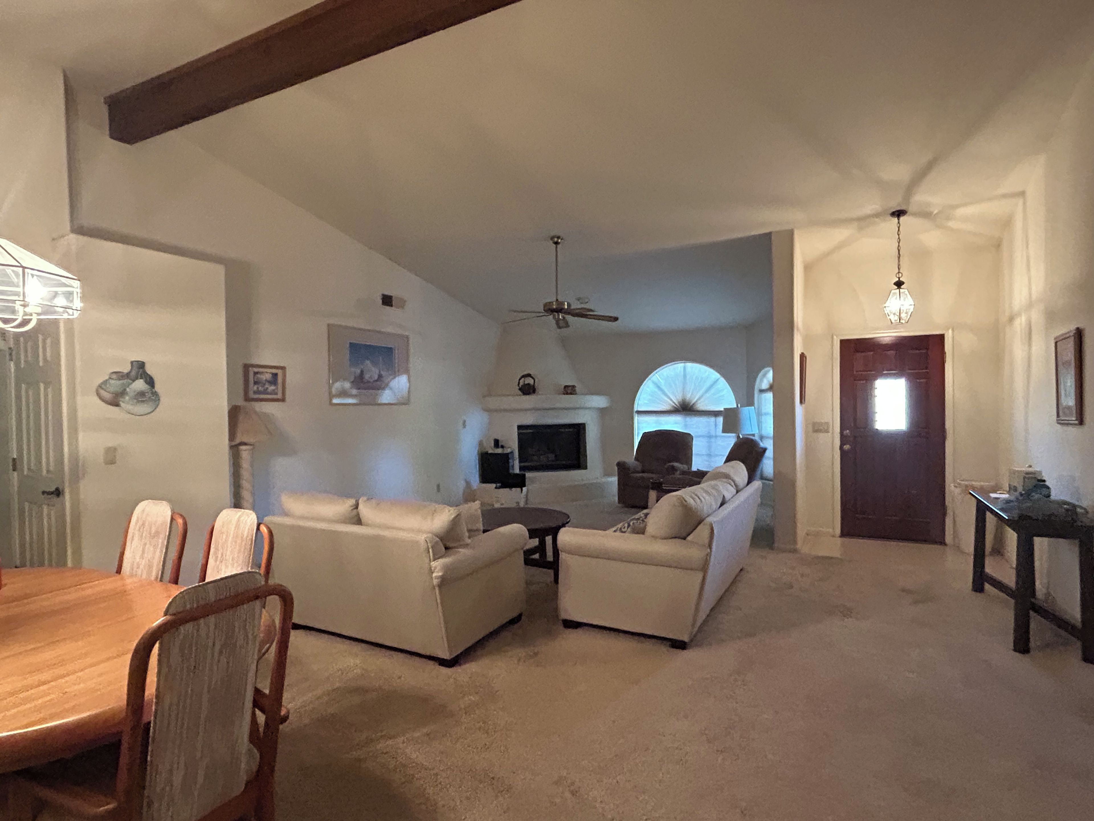 A spacious living room with a fireplace, a dining area with a wooden table and chairs, and a cozy seating area with sofas.
