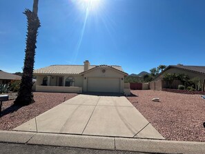 A residential property with a garage, a driveway, and a landscaped area with gravel and plants. - Charming 3 Bedroom 2 Bath Home in Fountain Hills with Pool and Mountain Views! (Fountain Hills)