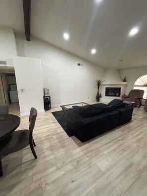 A spacious living area with a black sofa, a dining table with chairs, and a fireplace. - Charming 3 Bedroom 2 Bath Home in Fountain Hills with Pool and Mountain Views! (Fountain Hills)