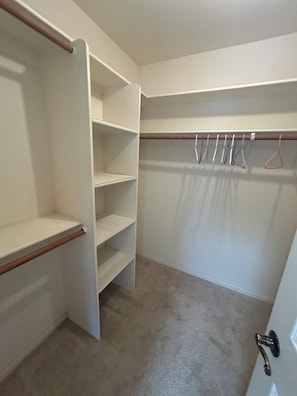 A walk-in closet with open shelves, a hanging rod, and a door with a handle. - Charming 3 Bedroom 2 Bath Home in Fountain Hills with Pool and Mountain Views! (Fountain Hills)