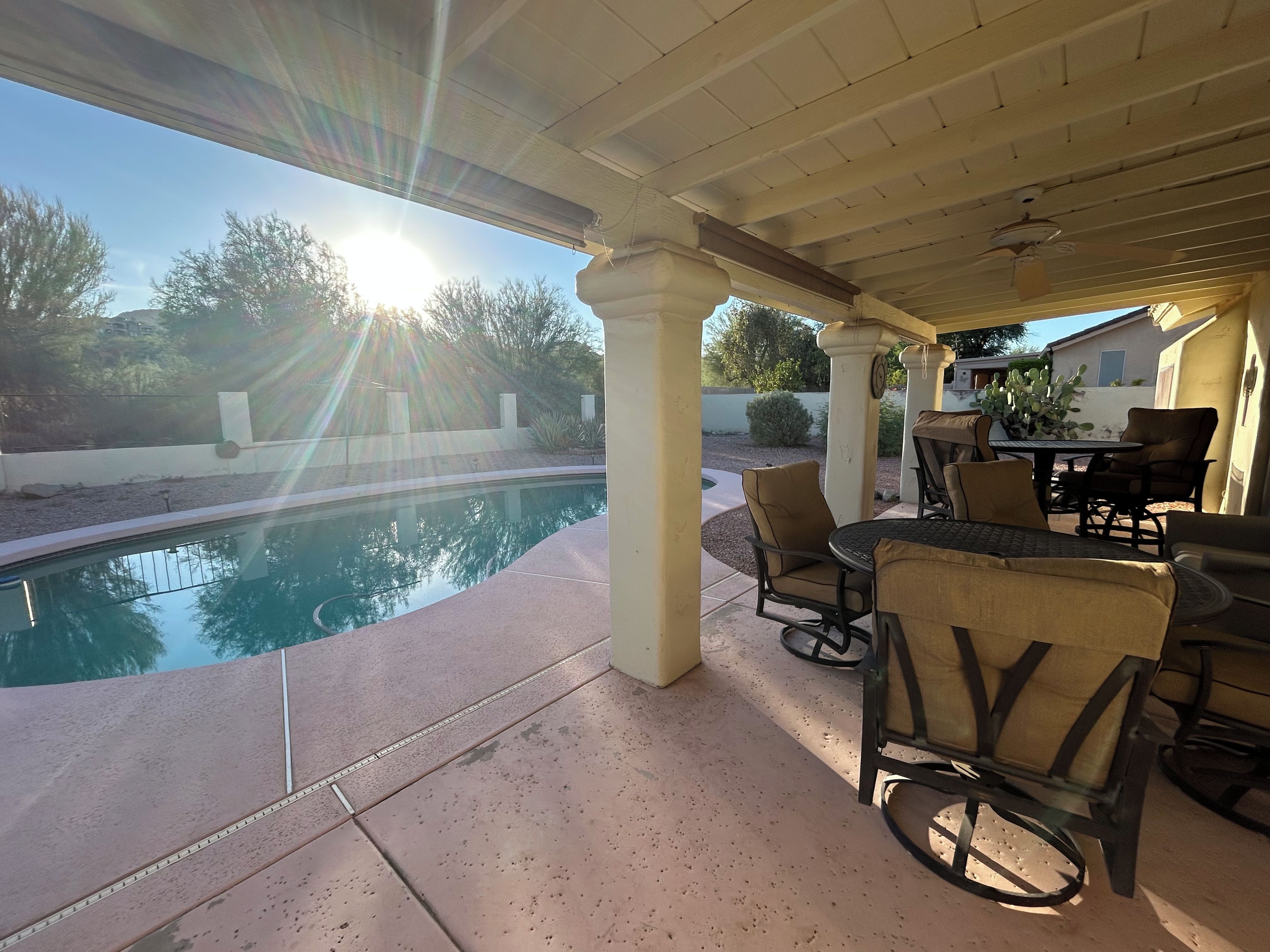 Un patio couvert avec une piscine, du mobilier d’extérieur et une vue sur le paysage environnant.