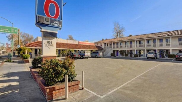 A motel with a large sign indicating it is a one-person motel. There is a street sign for 'Orville Express Valley' and '803 E Street.' The motel has a parking lot with several cars parked. - 2 Full Beds | Non-Smoking, Micfridge (Marysville)