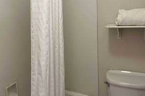 A bathroom with a white toilet, a white shower curtain, and a towel on a shelf. - 2 Queen Beds | Non-Smoking (Phoenix)