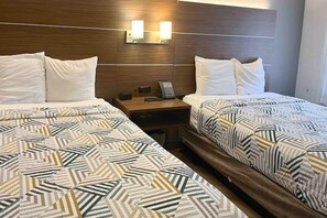 A hotel room with two beds, each with patterned bedding, a nightstand with a phone, and wall-mounted lighting. - 2 Queen Beds | Non-Smoking (Phoenix)