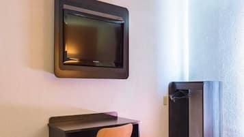 A room with a flat-screen TV mounted on the wall, a wooden chair, and a dark-colored cabinet.