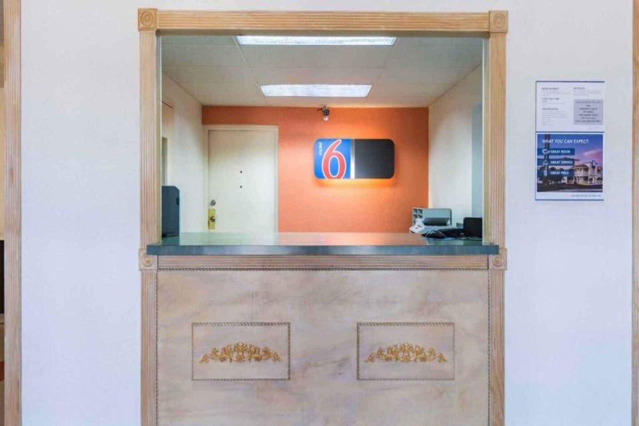 Uma área de recepção com balcão, porta e placa na parede com o número 6.