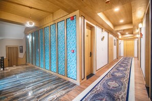 A hotel hallway with wooden paneling, a patterned carpet, and a series of doors. - The Grand Cliff By Marvilla (Anantnag)