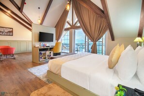 A bedroom with a large bed, a TV, a desk with a chair, and a balcony with a view. - The Grand Cliff By Marvilla (Anantnag)