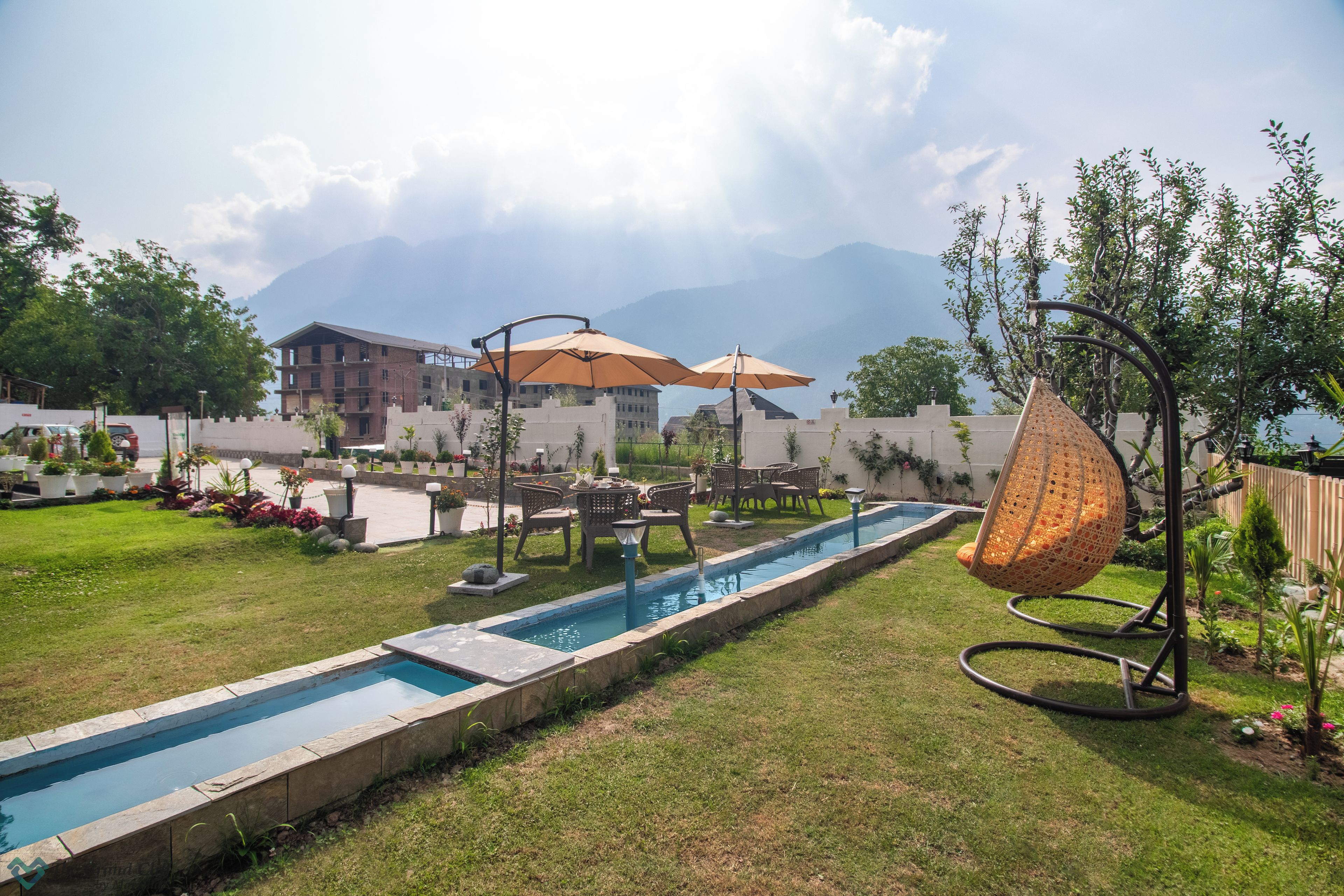 A swimming pool with a surrounding deck, outdoor furniture, and a hanging chair.
