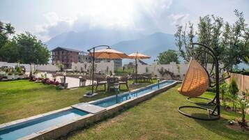 A swimming pool with a surrounding deck, outdoor furniture, and a hanging chair.
