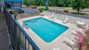 A rectangular pool with a diving board and lounge chairs.