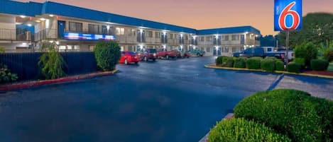 A motel with a large parking lot, multiple buildings, and a prominent '6' sign.