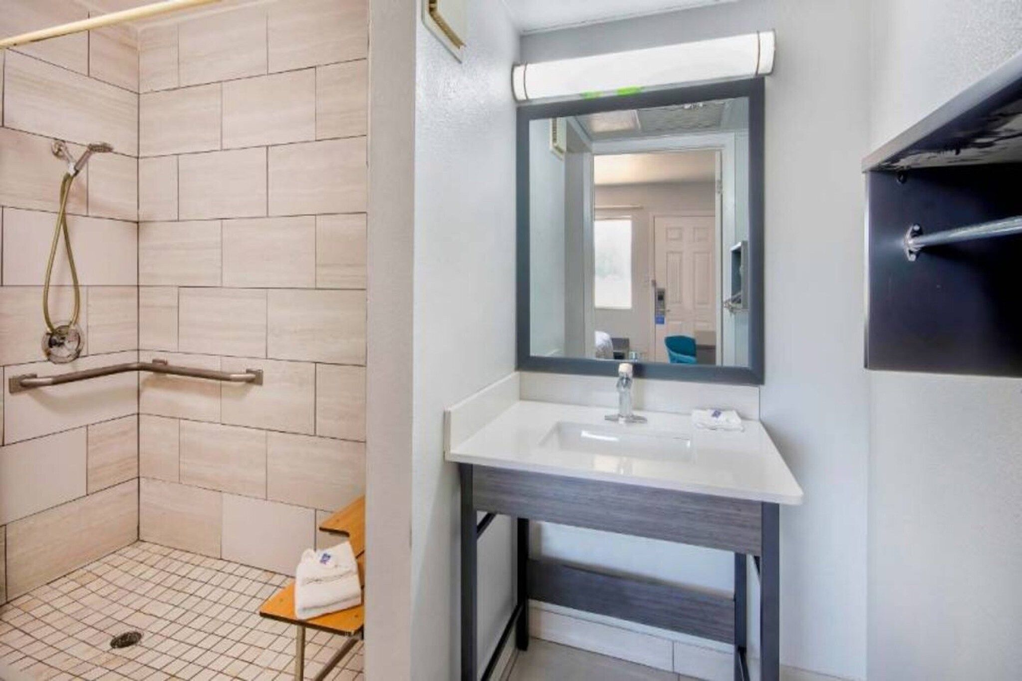 Un baño con ducha, lavamanos y espejo.